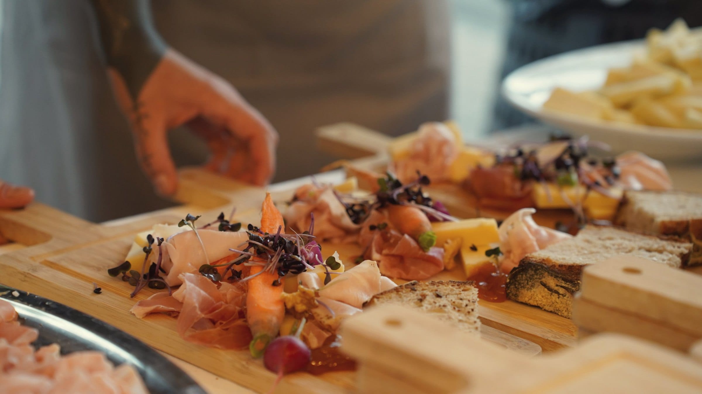 Apérobrett mit Prosciutto, Käse und Microgreens wird angerichtet: Apéro-Catering Zürich