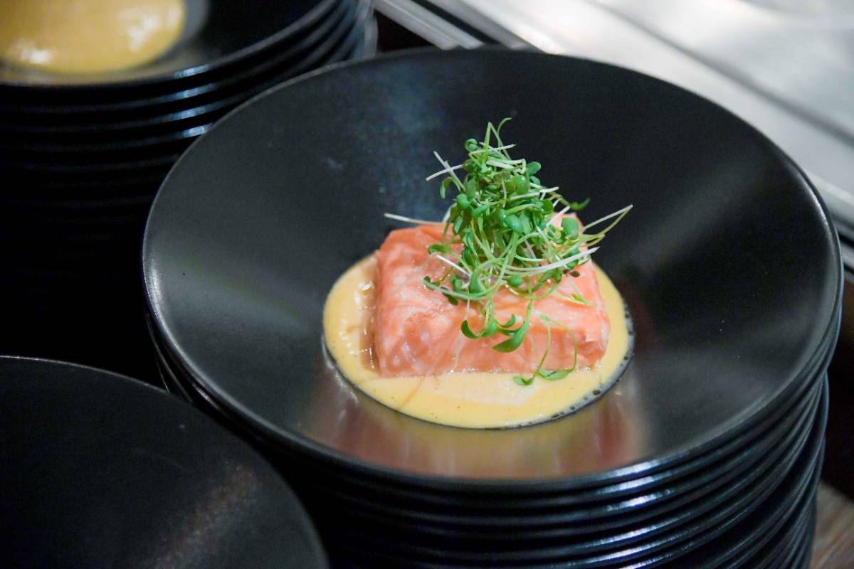 Salmon on a pale sauce topped with cress in a black bowl: a course for boardroom dining in Zürich