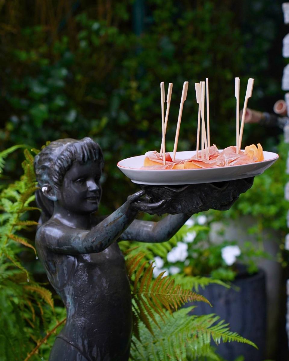 Bronze statue holding a plate of melon and prosciutto: a playful apéro display, Zürich catering