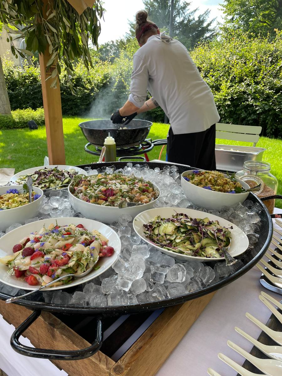 Buffet: Salate auf Eis, dahinter der Koch an der Pfanne im Garten, Gartenfest mit Catering aus Zürich