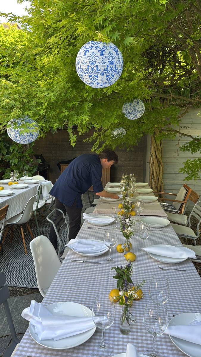 Lange Tafel im Garten unter Lampions, mit Zitronen und Wiesenblumen gedeckt: Tischdekoration für einen Anlass in Zürich