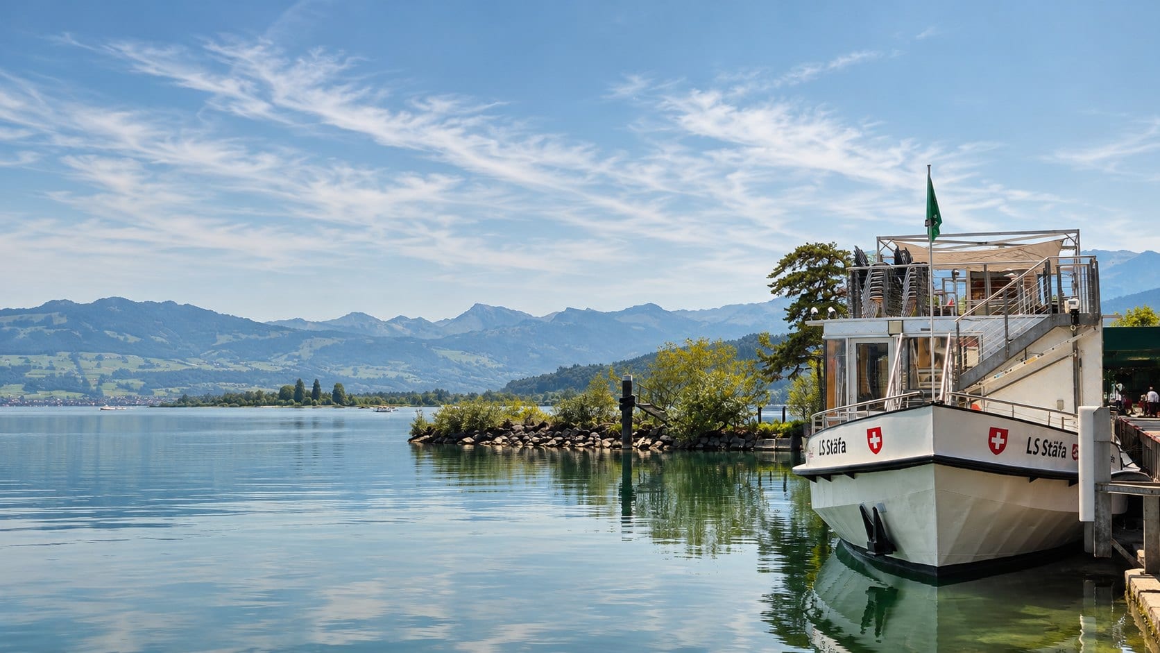 Schiff am Steg, dahinter der See und die Berge: Eventlocation am Wasser bei Zürich