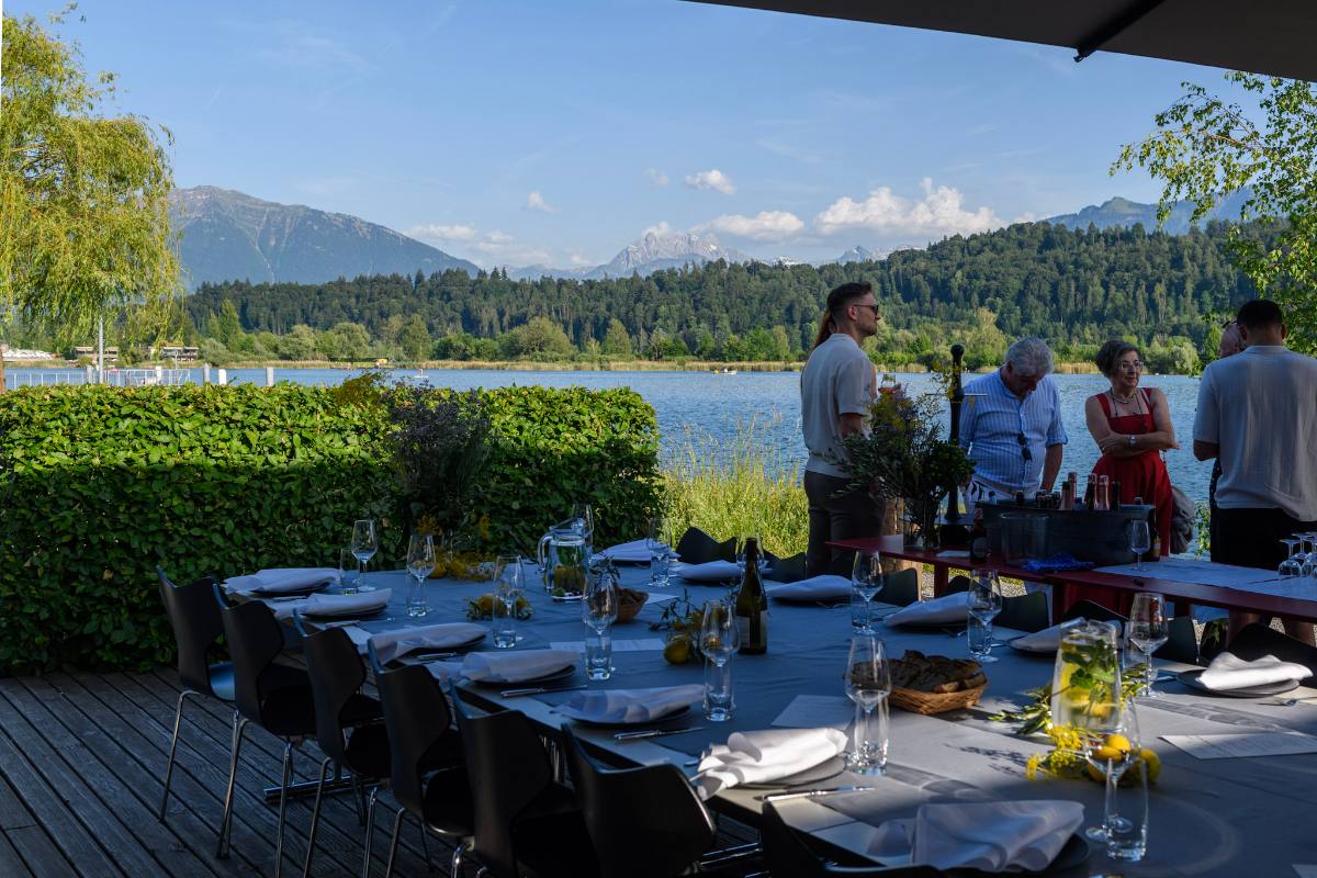 Gedeckte Tafel auf einer Seeterrasse, Gäste beim Apéro und Berge im Hintergrund: Eventlocation bei Zürich