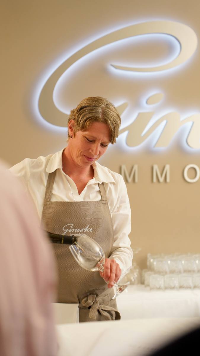 Server pouring wine in front of the Ginesta Immobilien logo: company event with catering in Zürich