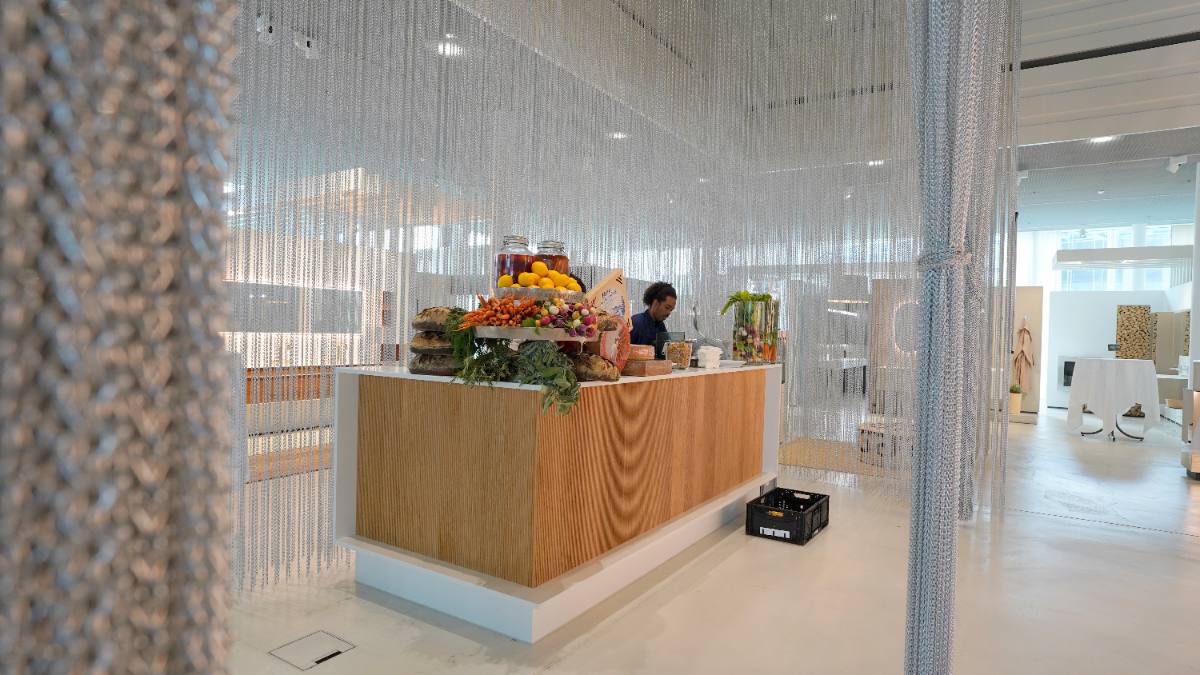Market stall with cheese, bread and fresh vegetables in a bright office behind chain curtains: corporate event with catering in Zürich