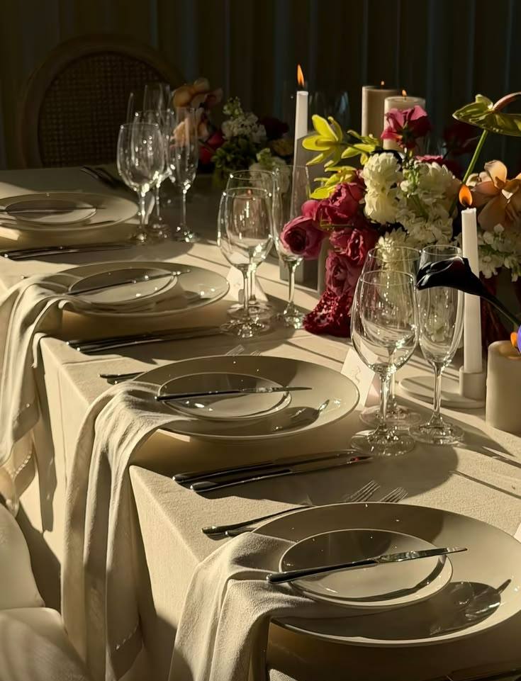 Dinner table in evening light with candles, wine glasses, linen napkins and flowers: catered dinner in Zürich