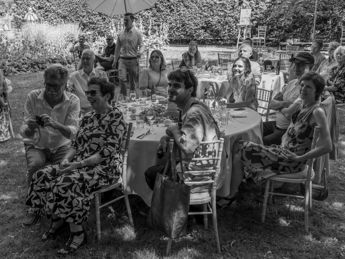 Wedding guests at round tables in a garden listening to a speech: garden wedding with wedding catering from Zürich