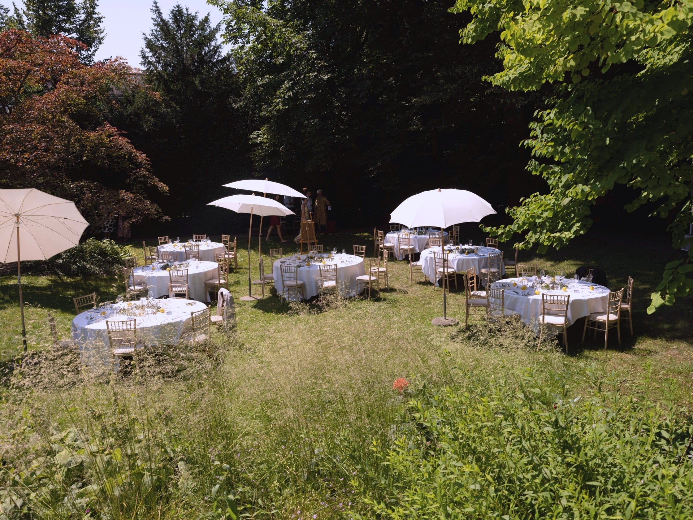 Runde Tafeln und Sonnenschirme für eine Gartenhochzeit: Hochzeitscatering Zürich