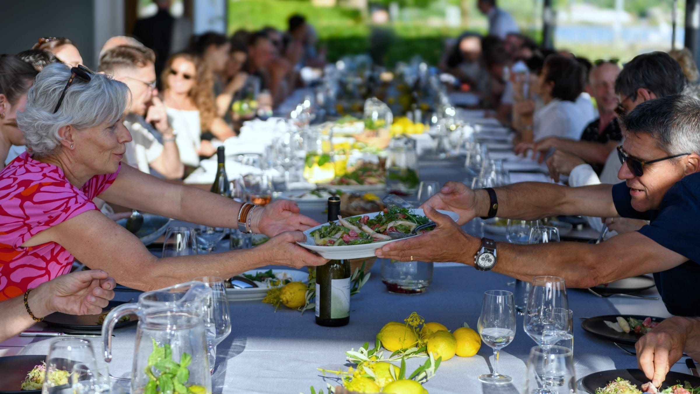 Gäste reichen sich an einer langen Tafel die Teller weiter: private Feier im Tavolata-Stil, Catering Zürich