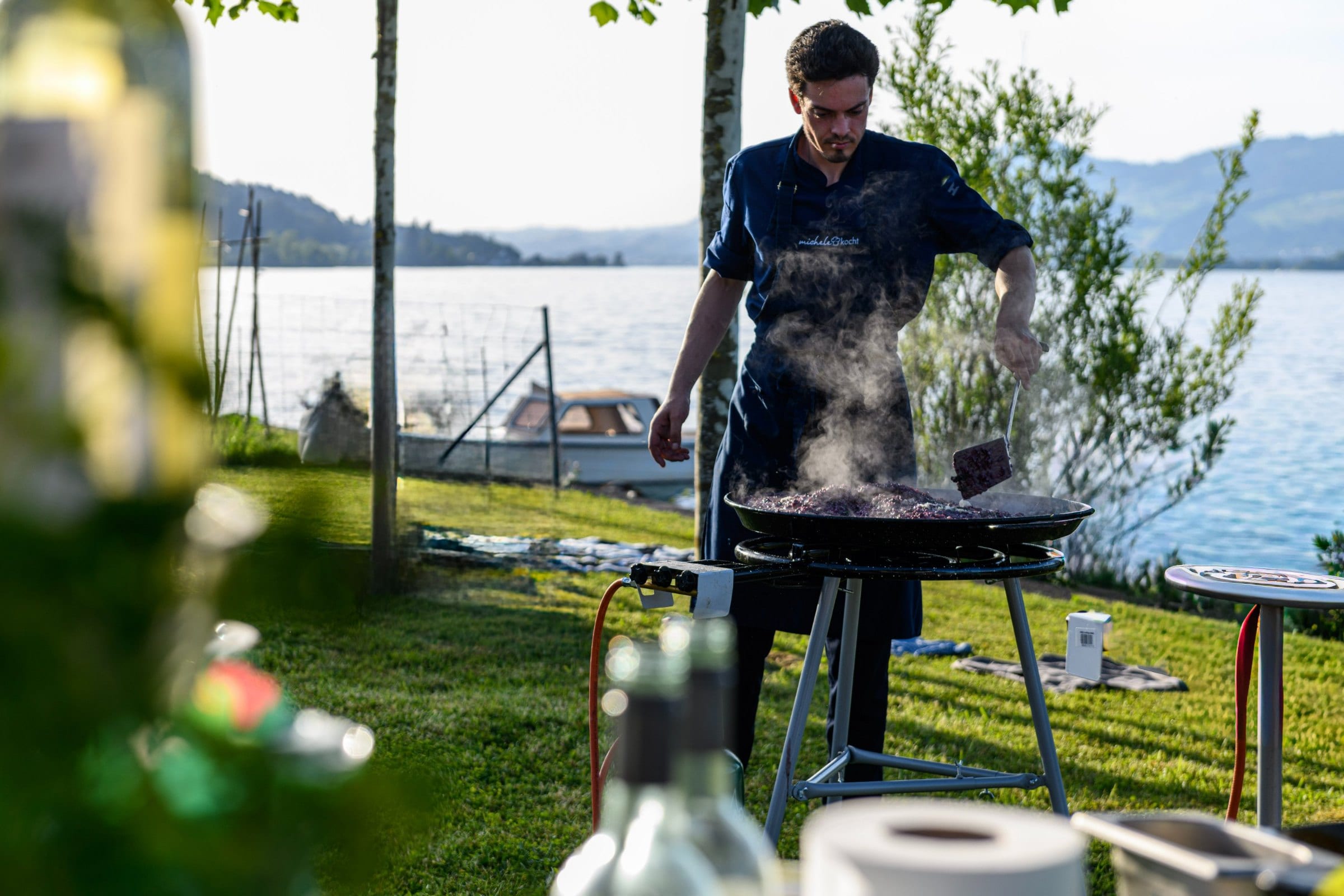 Live cooking by the lake: chef at a large pan on the lawn, event catering on a lake near Zürich