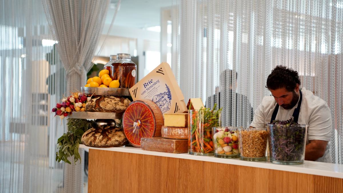Market stall with Brie from Sternenberg, alpine cheese, sourdough loaves, radishes and carrots, a chef at work behind it: company event in Zürich