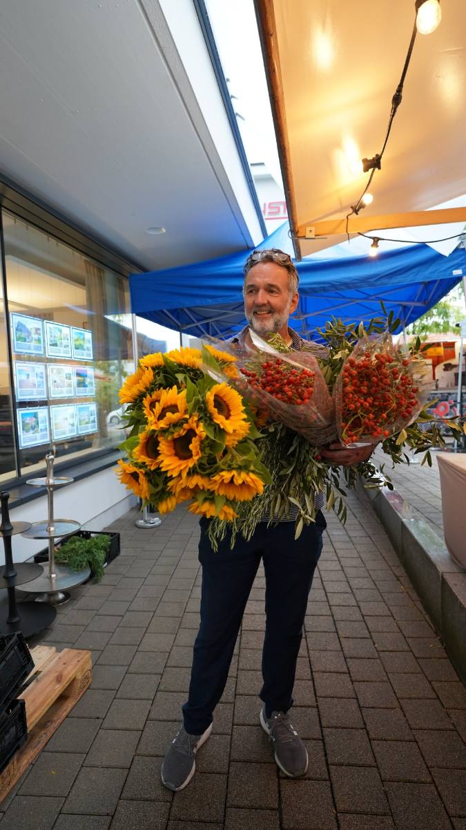 Michele carrying sunflowers, rosehips and olive branches for event decoration in Zürich