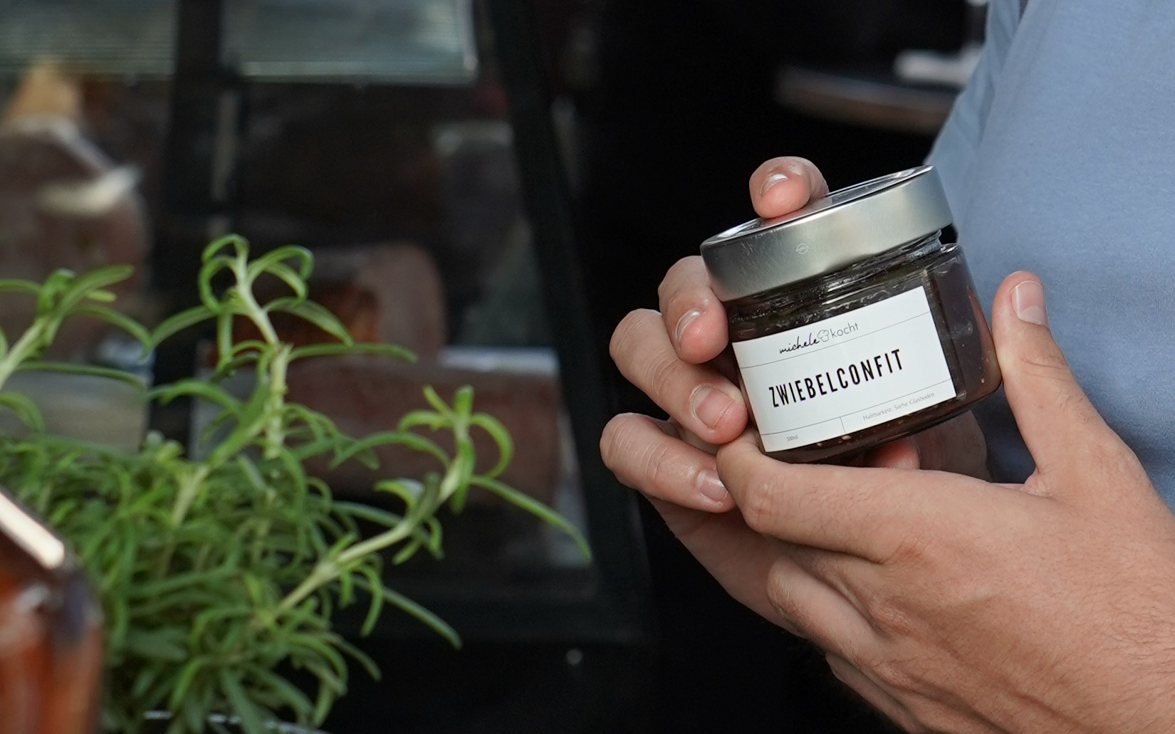 Hände halten ein Glas hausgemachtes Zwiebelconfit von MicheleKocht am Marktstand in Zürich